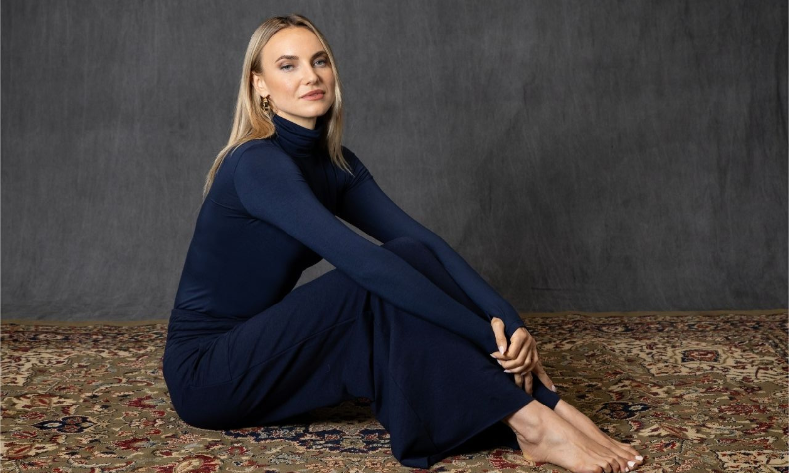 Woman sitting on the carpet wearing cozy dark blue fall outfit