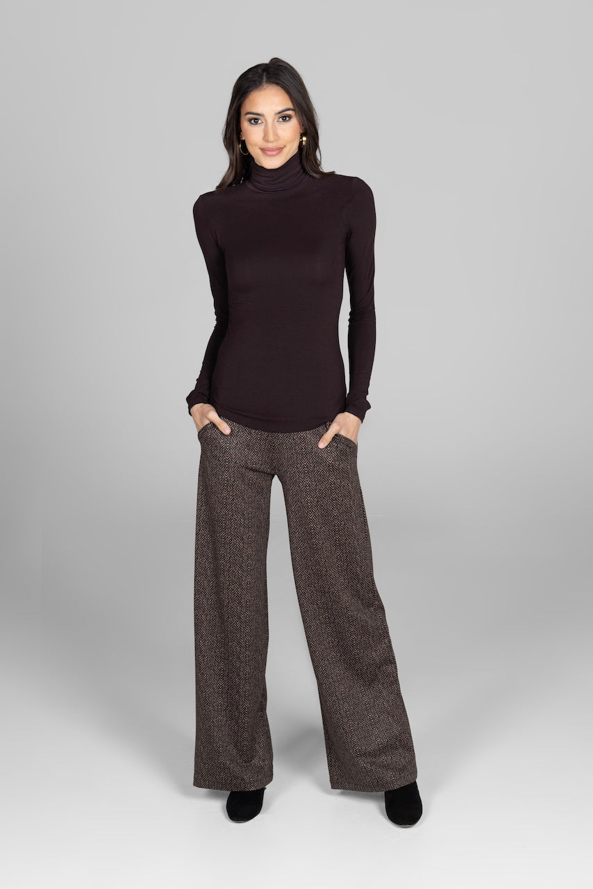 Woman wearing brown long sleeve turtleneck with brown herringbone printed wide leg pants