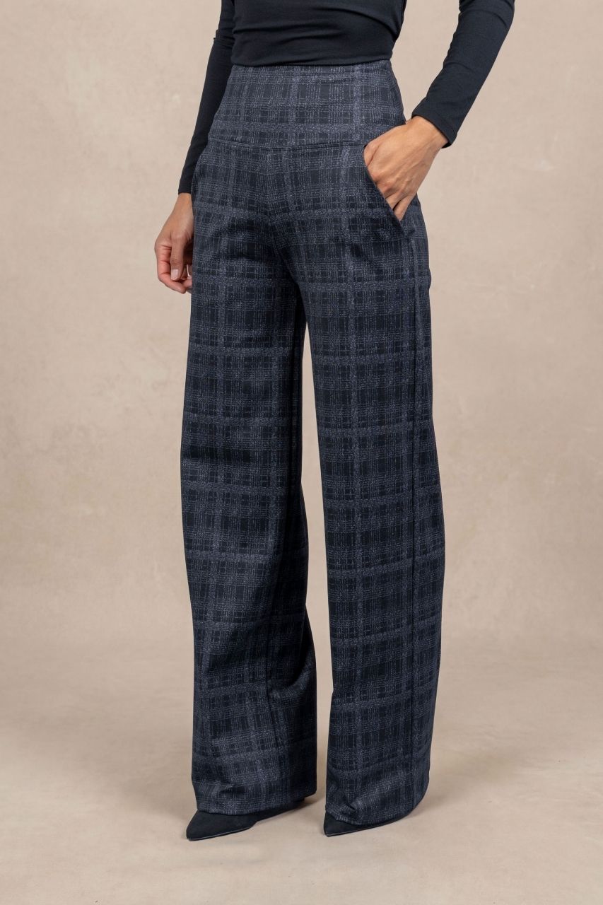 Woman wearing grey plaid pants on a beige background
