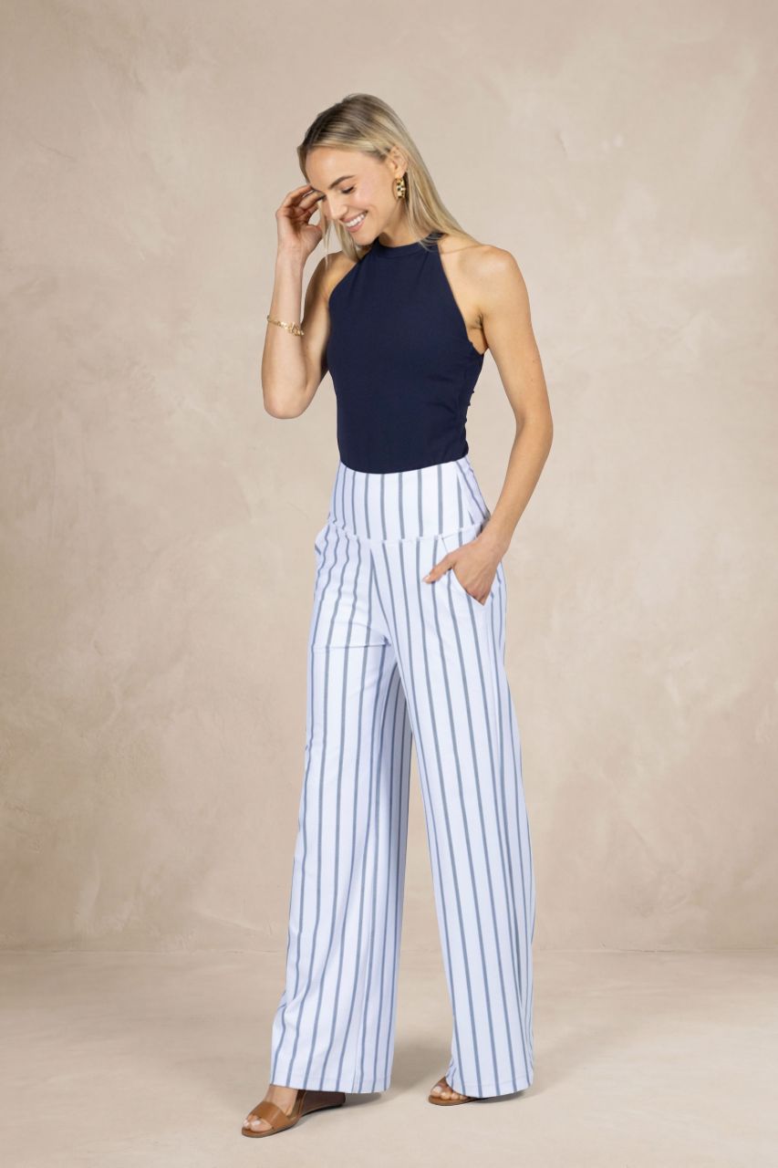Woman wearing a navy top and white striped pants against a beige background