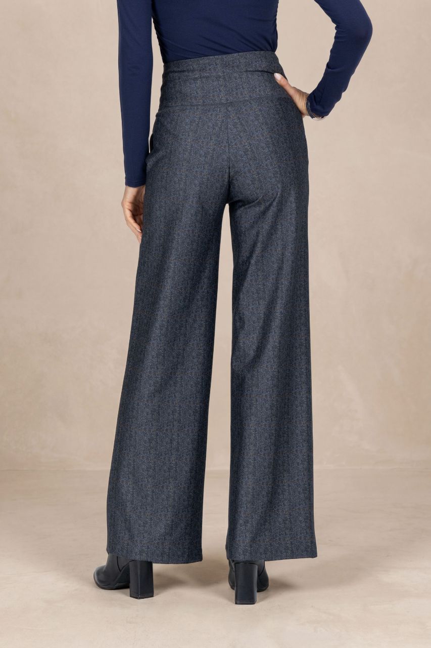 Back view of a person wearing tartan high-waisted pants on a beige background