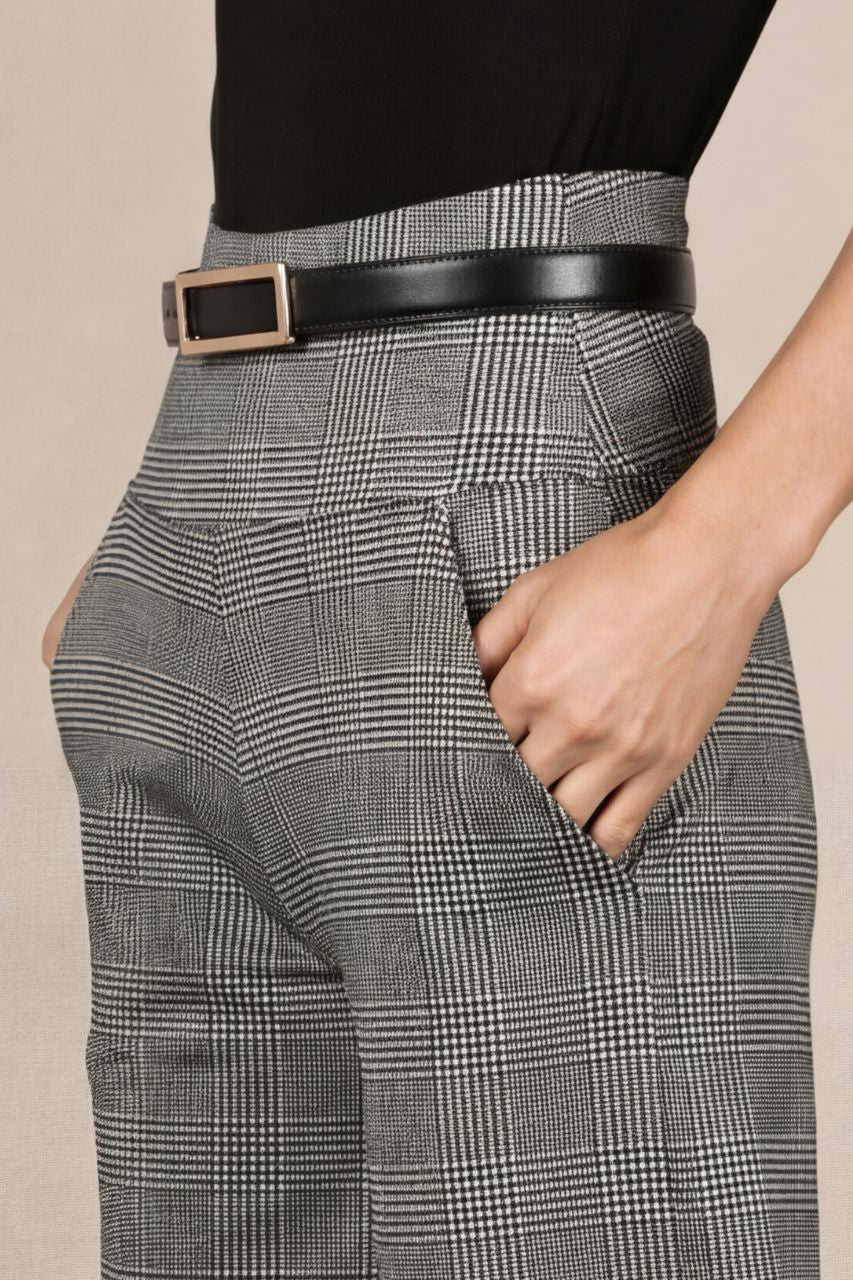 Person wearing gray plaid pants with a black belt on a beige background