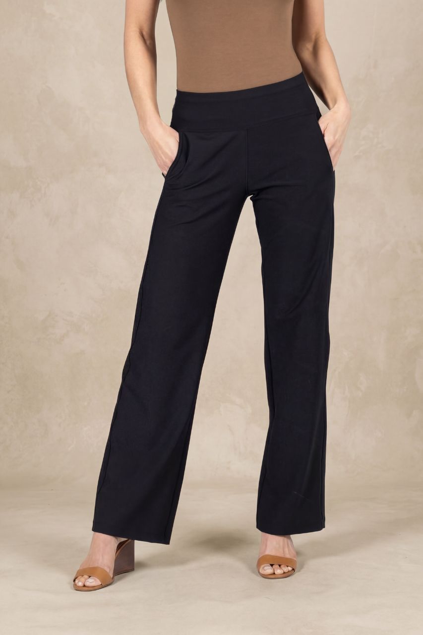 Person wearing black mid rise pants on a beige background