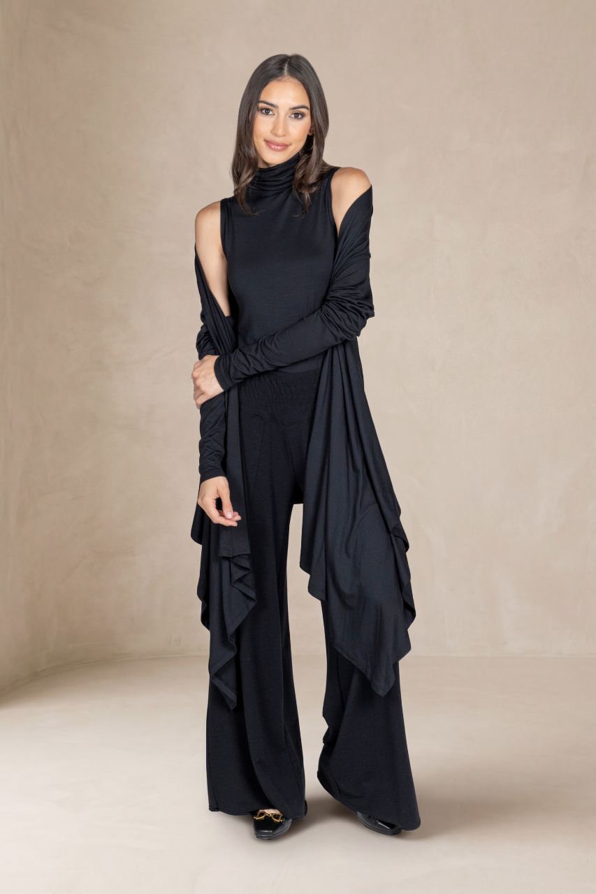 Woman wearing a black outfit with a cardigan against a beige background