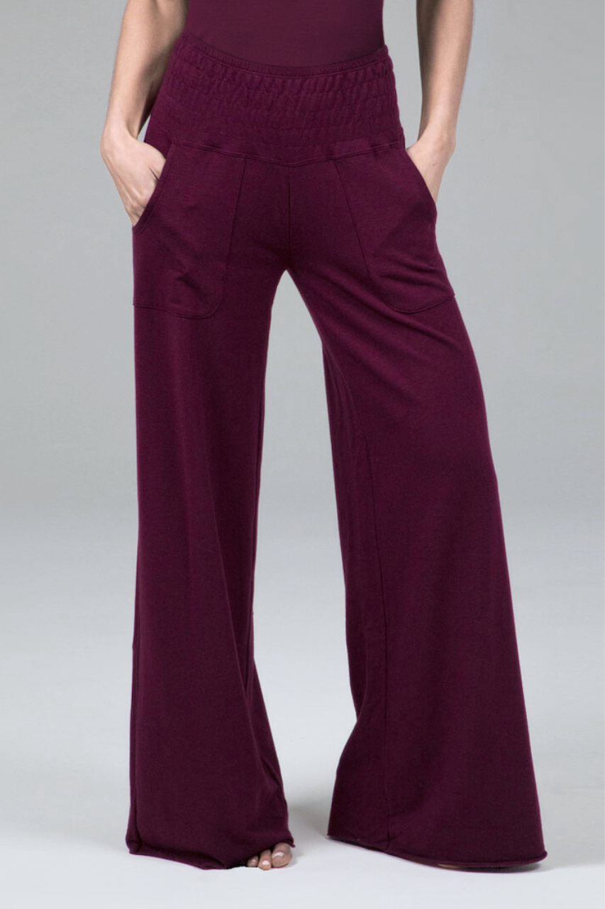 Burgundy wide-leg pants worn by a woman on a plain background