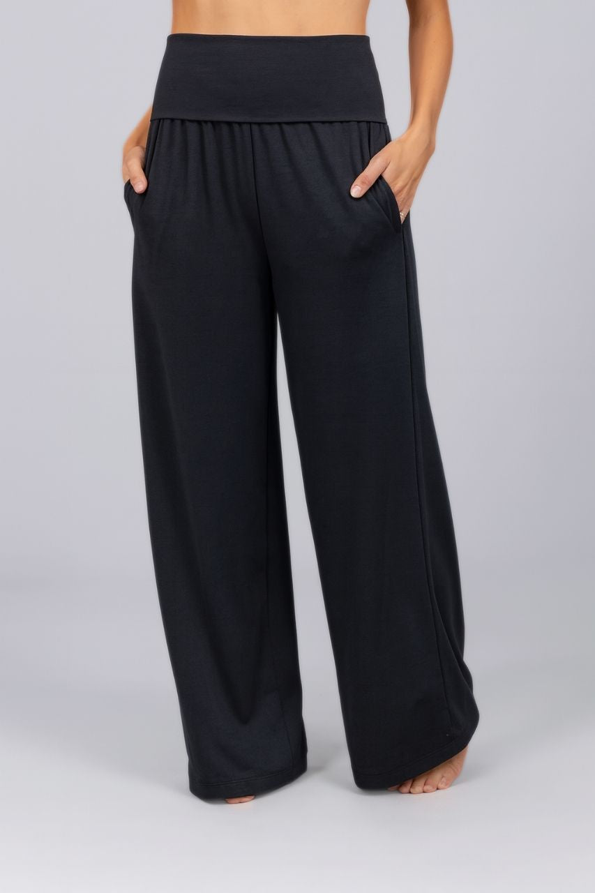 Black high waisted wide-leg pants worn by a woman on a plain background