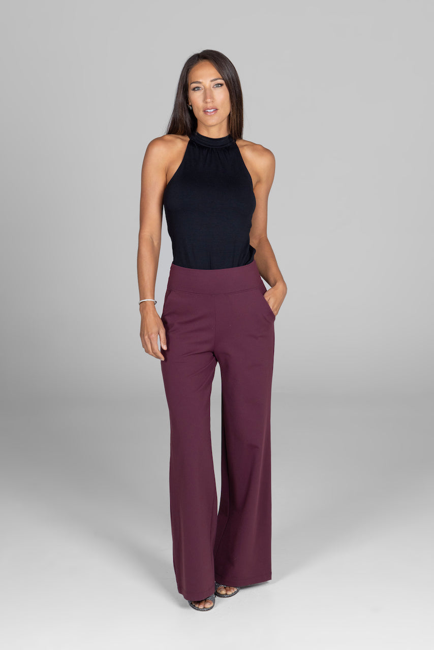 Woman wearing wide leg high waist ed burgundy pants with a black halter top