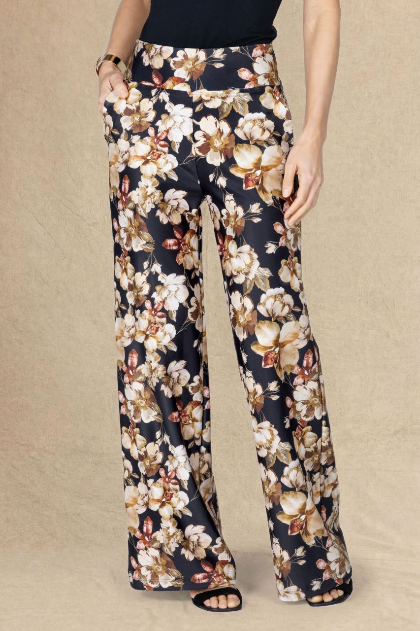 Front view of a woman wearing fall floral wide leg pants on a beige background