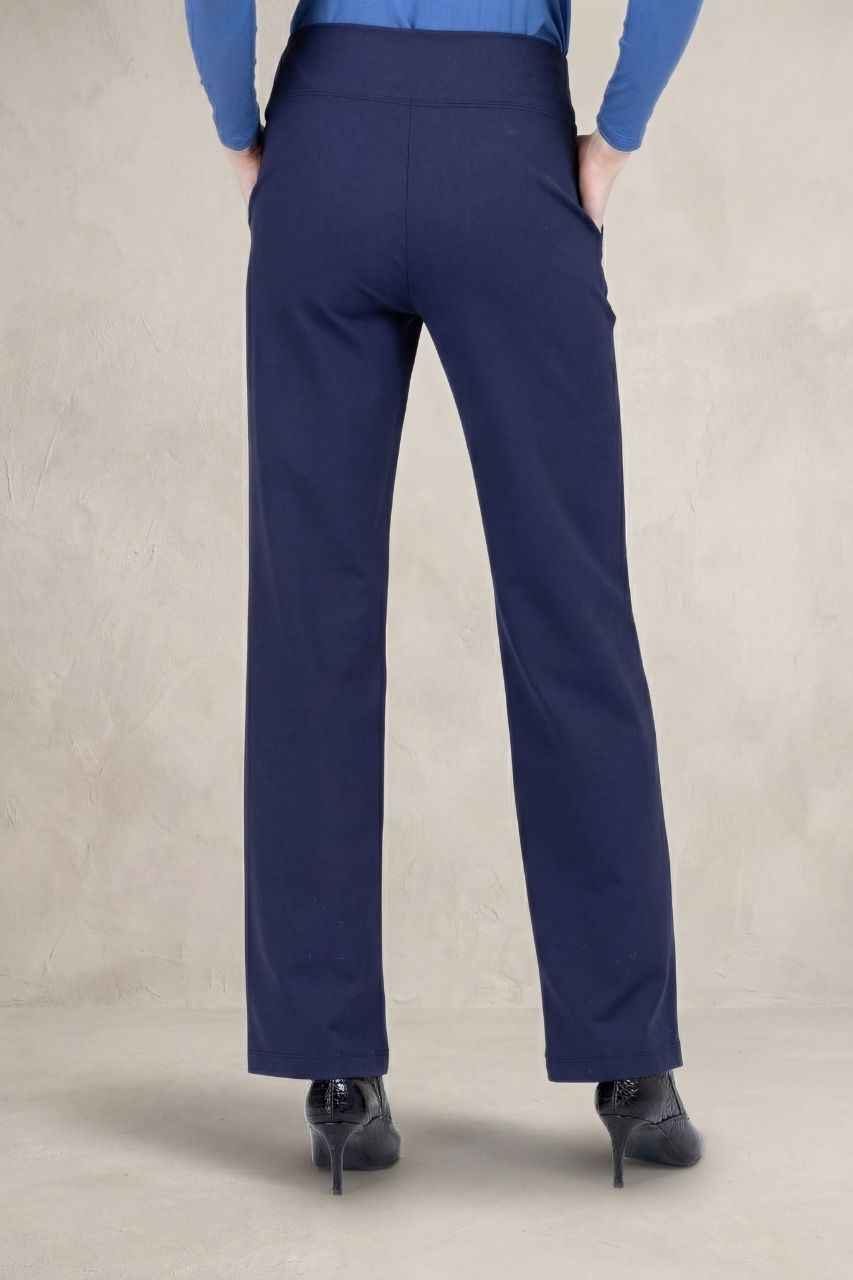 Back view of navy blue straight leg pants in front of a beige background