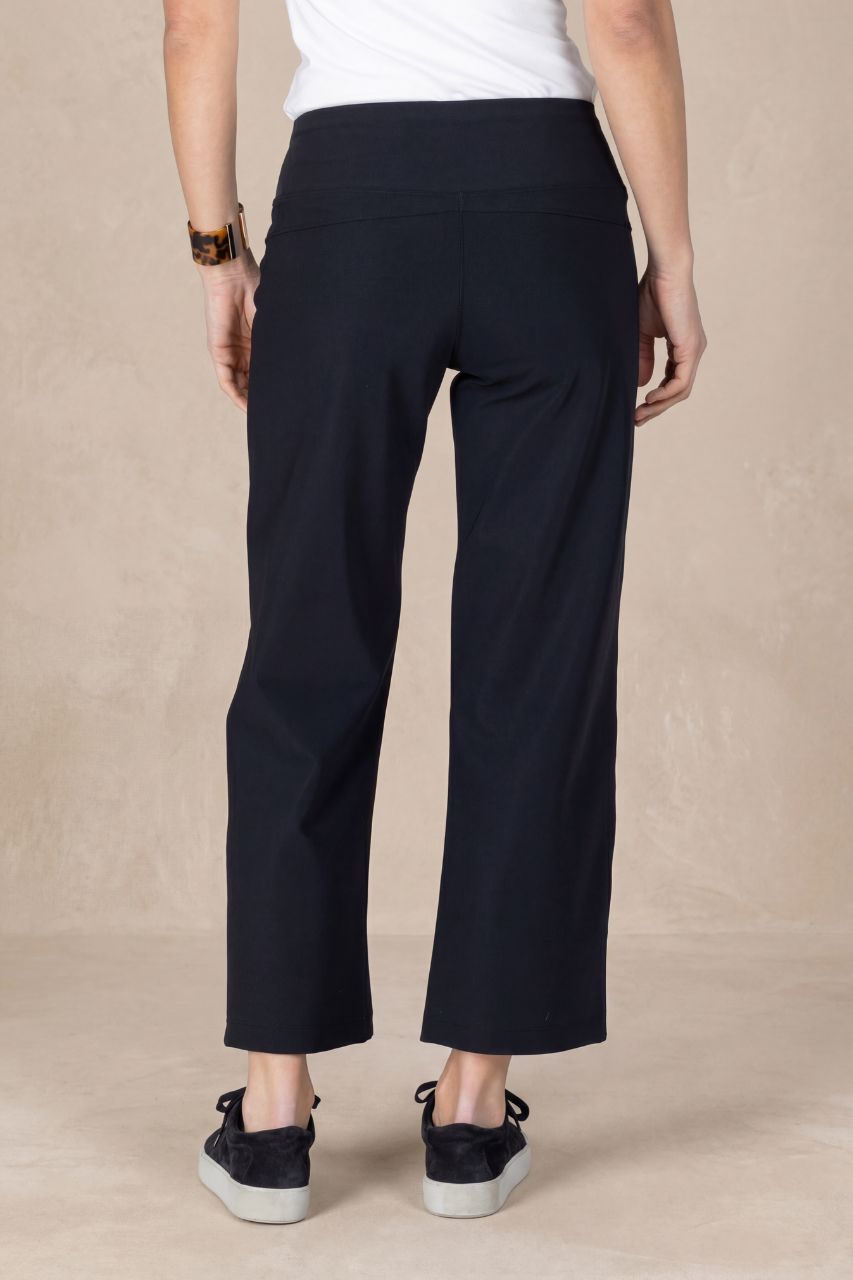 Person wearing black cropped pants on a beige background