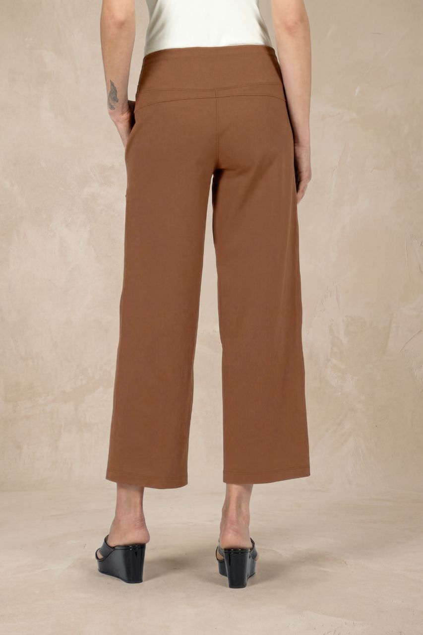 Back view of brown ankle pants worn by a person on a beige background