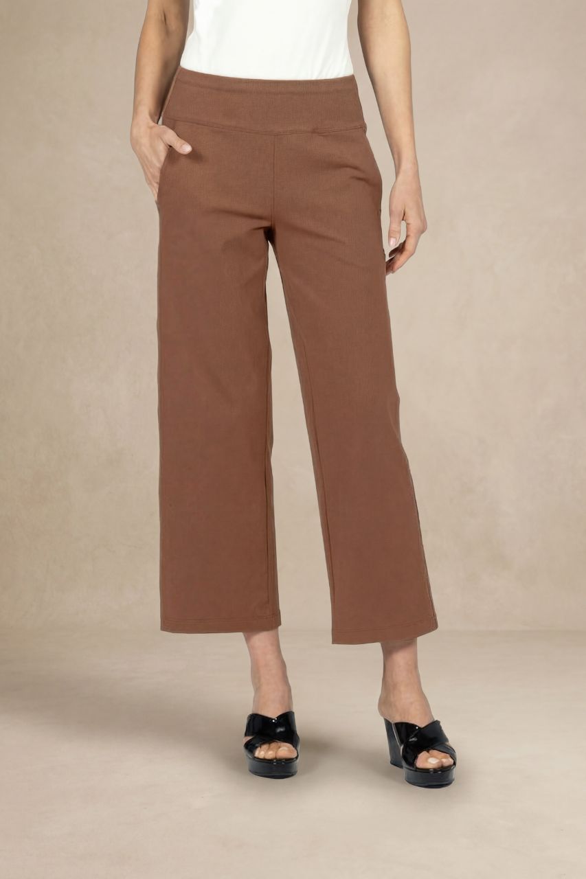 Person wearing brown ankle pants on a beige background