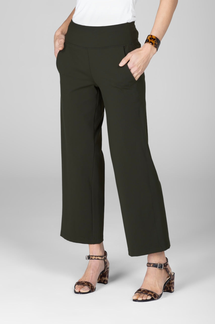 A person wearing green ankle-length traveler pants with a white top, standing