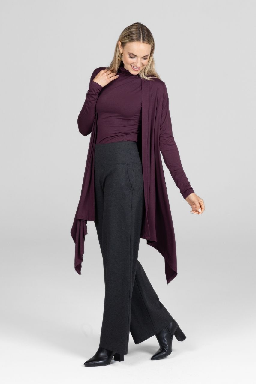 Woman wearing a long burgundy cardigan over a matching top and charcoal pants on a white background