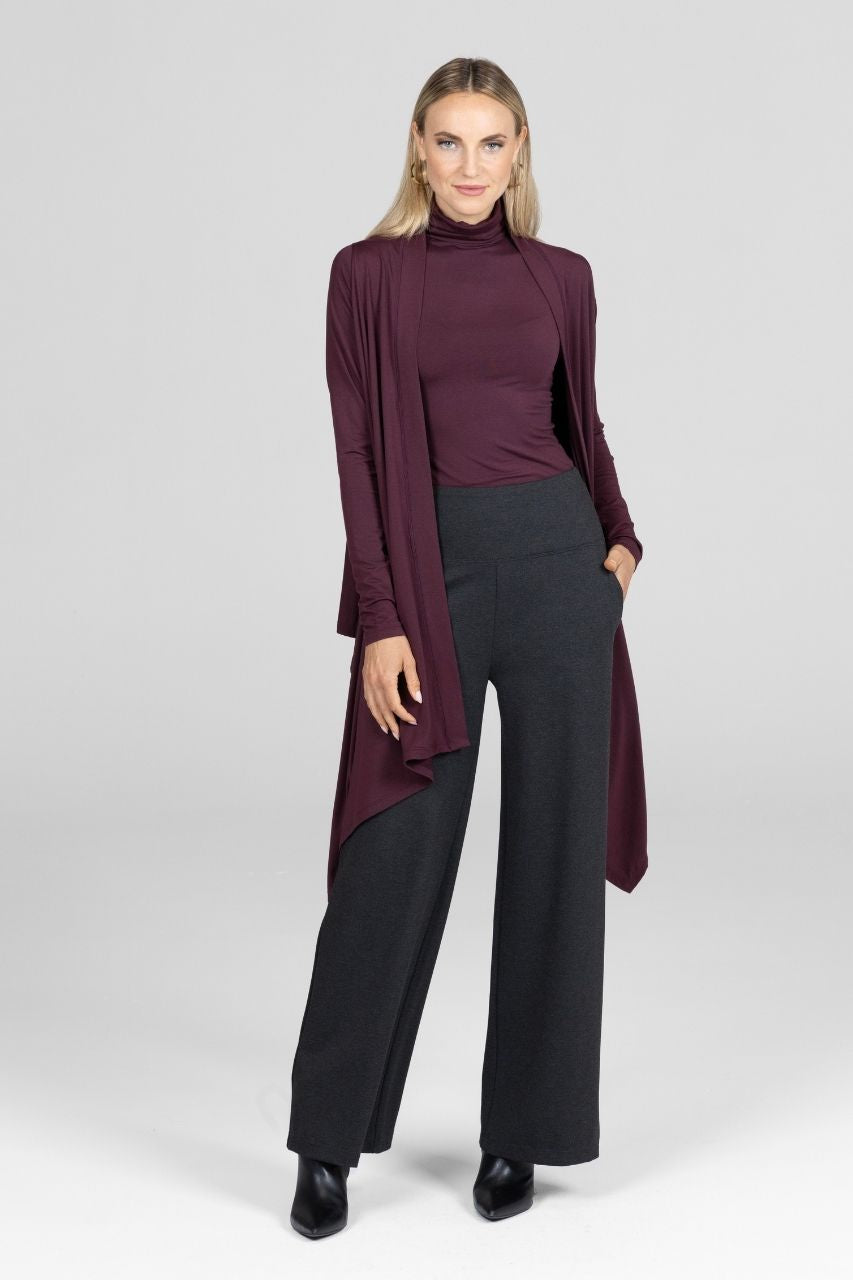 Woman wearing a burgundy long-sleeve cardigan and charcoal pants on a white background