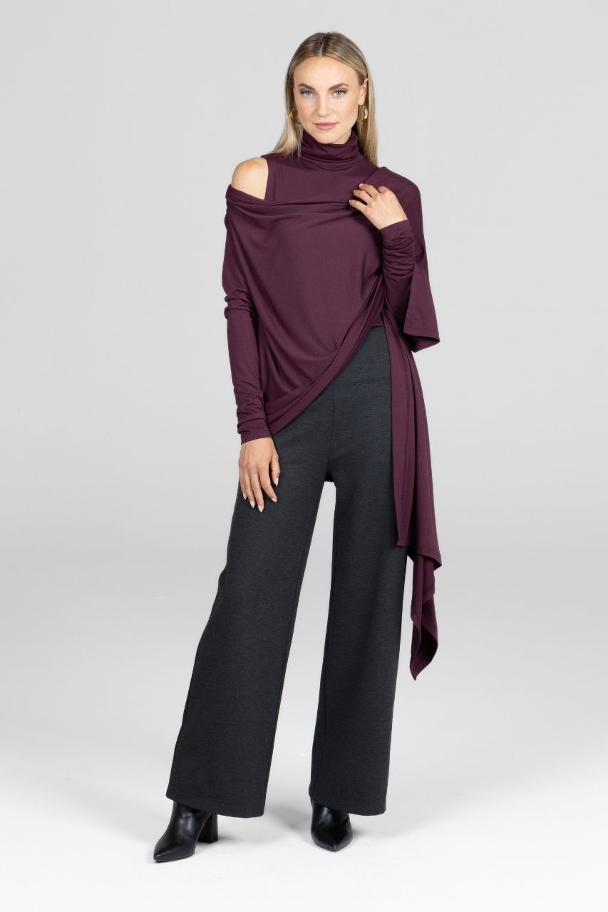 Woman wearing a burgundy cardigan with a matching sleeveless turtleneck and charcoal pants on a white background