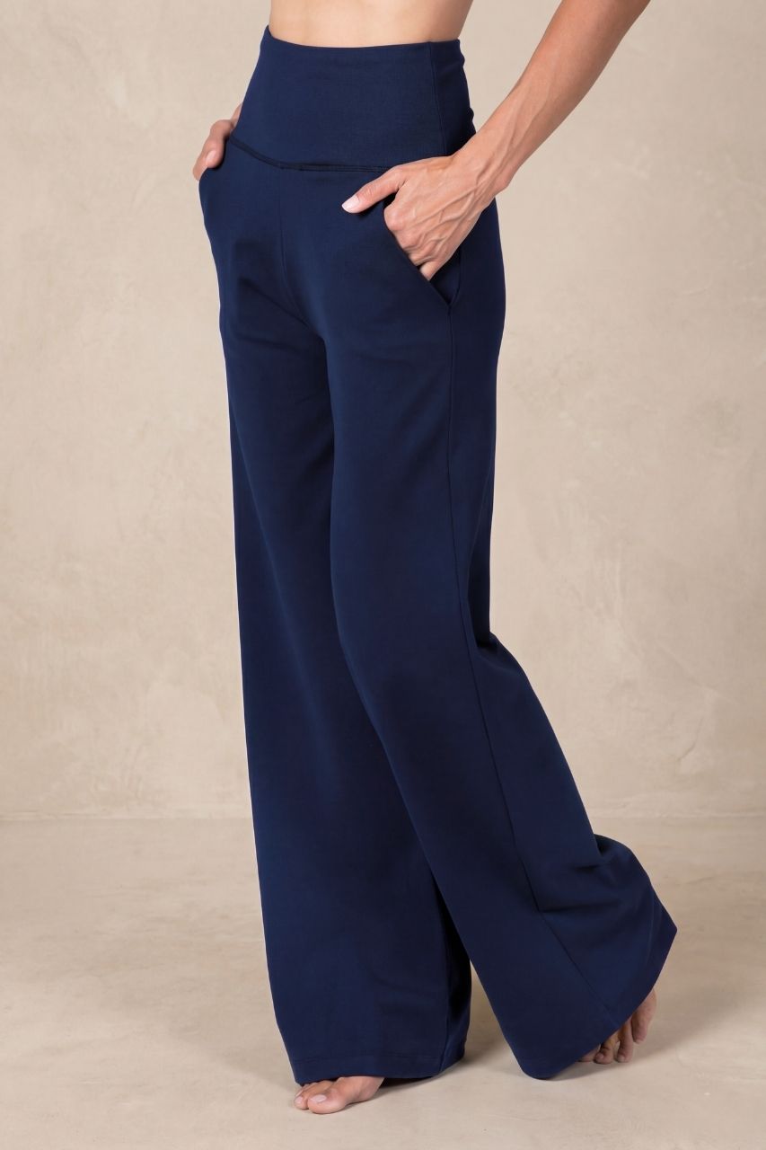 Model wearing navy blue high waist wide leg pants on a beige background