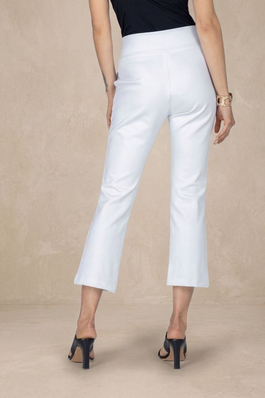 Person wearing white ankle pants on a beige background