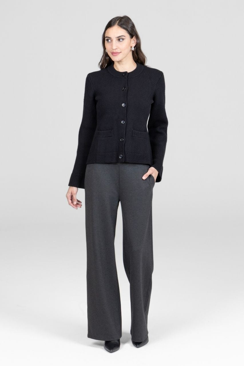 Woman wearing a black button cardigan and gray wide leg pants on a white background