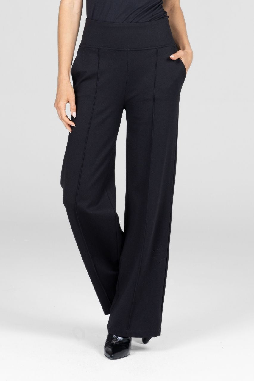 Black wide-leg pants with pintucks worn by a woman on a white background