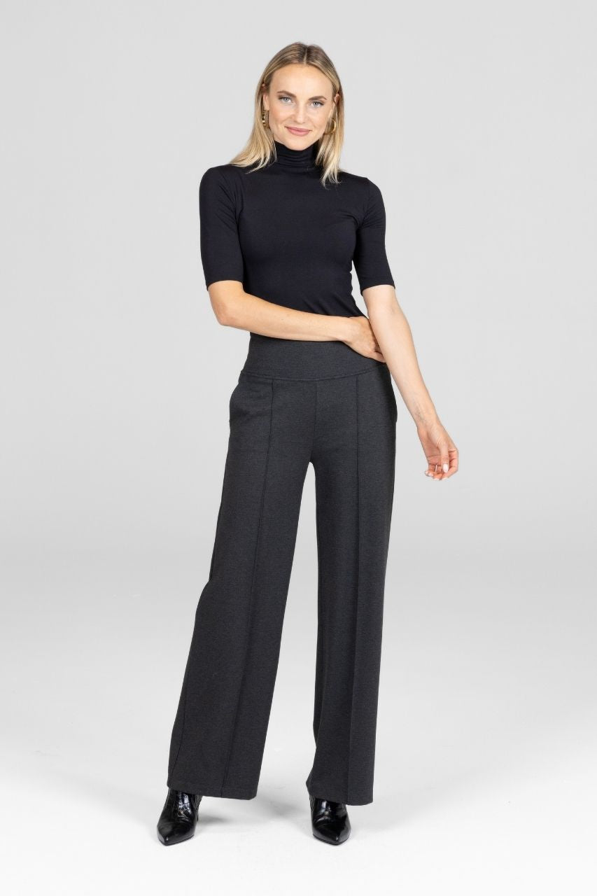 Woman wearing a black mock neck tee and gray high waist wide-leg pants on a white background