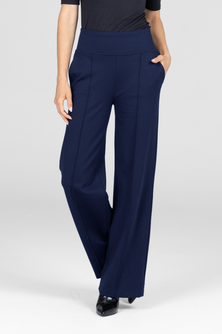 Navy blue wide-leg pants worn by a woman on a white background with one hand in the front pocket