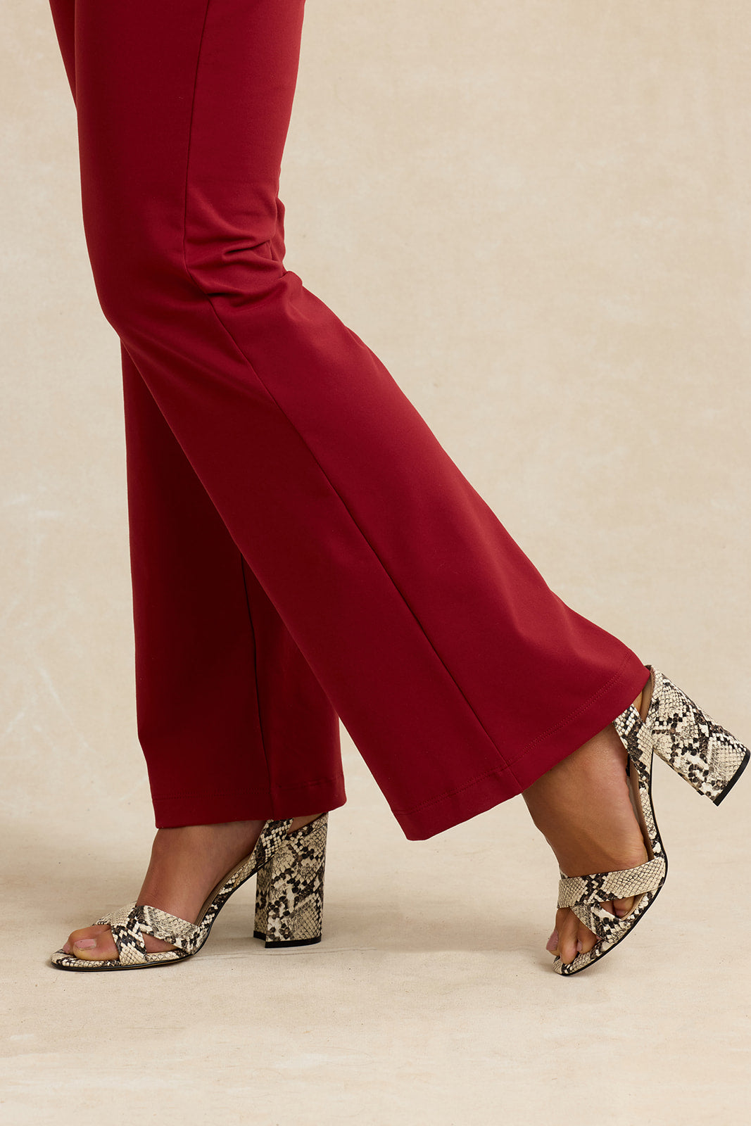 Close up view of a brick red flared pant leg