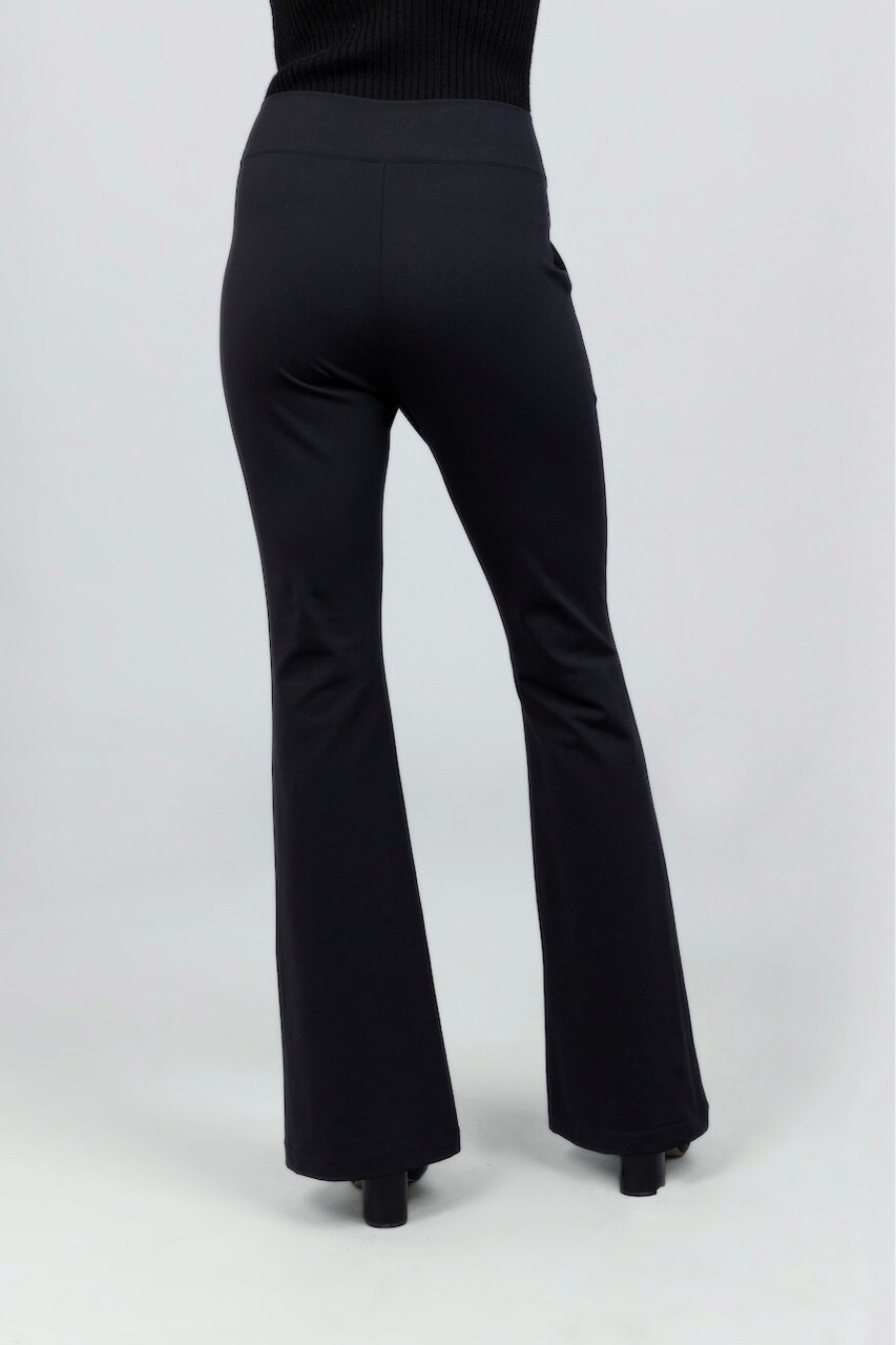 Back view of black flared pants worn by a woman on a white background