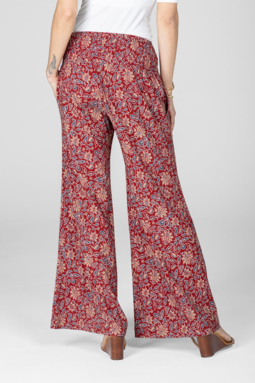 Back view of red motif printed pants with wide leg and high rise smocked waistband