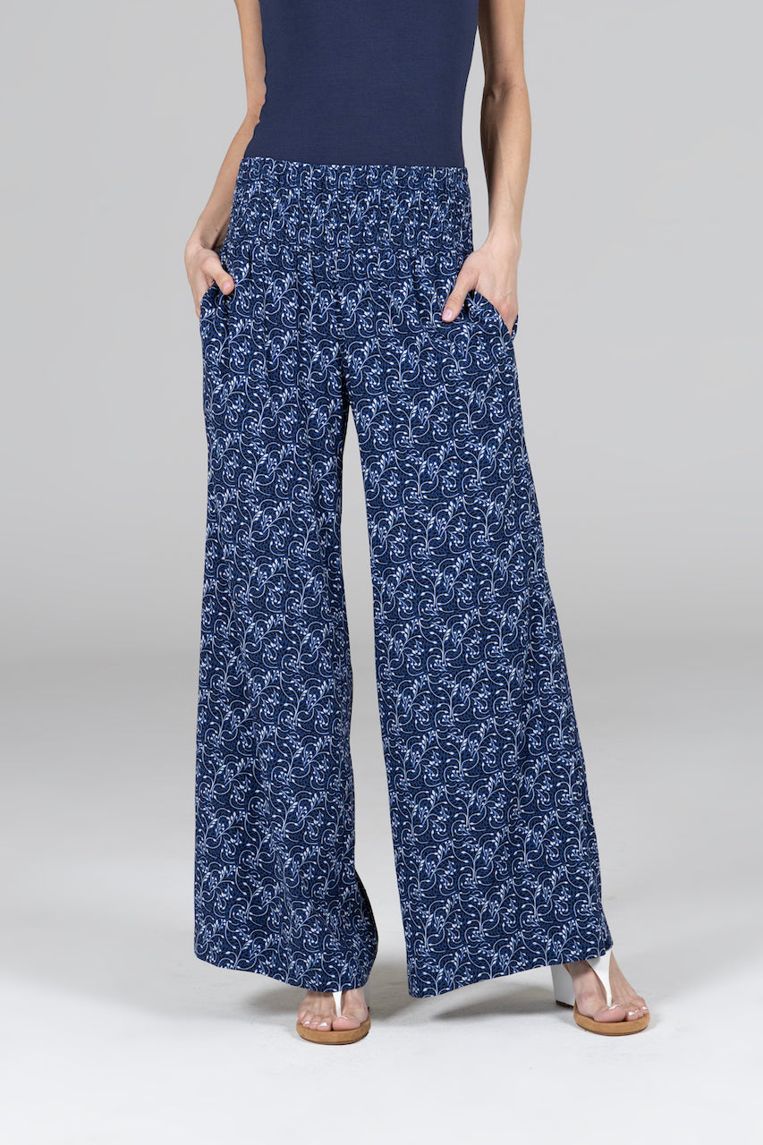 Woman wearing blue vines printed pants. High rise fit with smocked waistband and wide leg opening