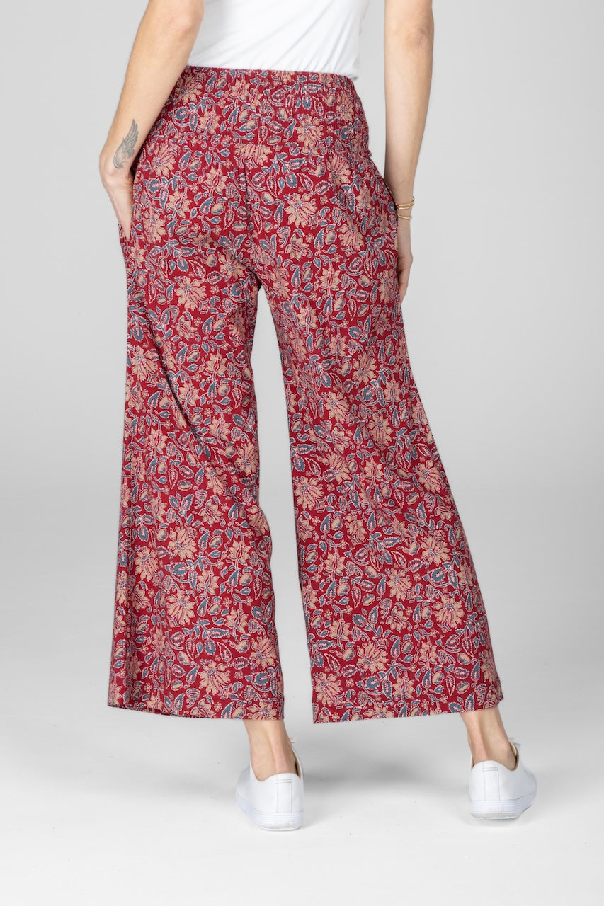 Back view of woman wearing red motif printed ankle pants with a smocked waistband