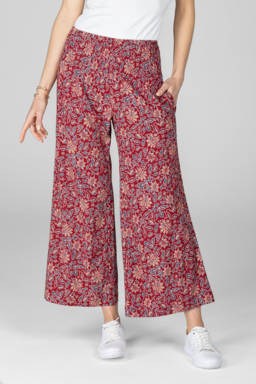 A pair of red motif printed ankle pants with a smocked waistband and side pockets, worn with a white top and white sneakers.