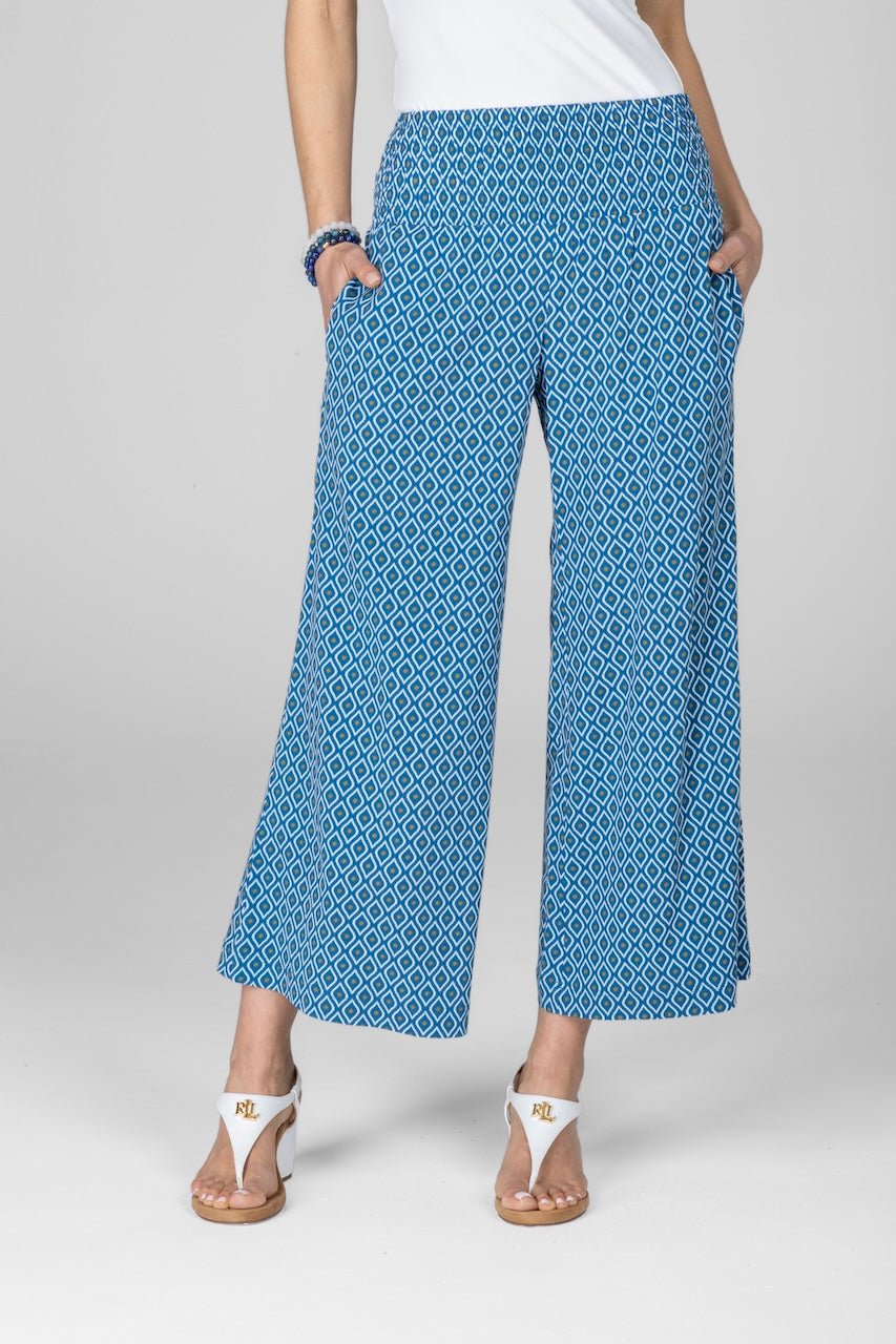 A pair of blue ankle pants with a geometric summer print, featuring a smocked waistband and side pockets.