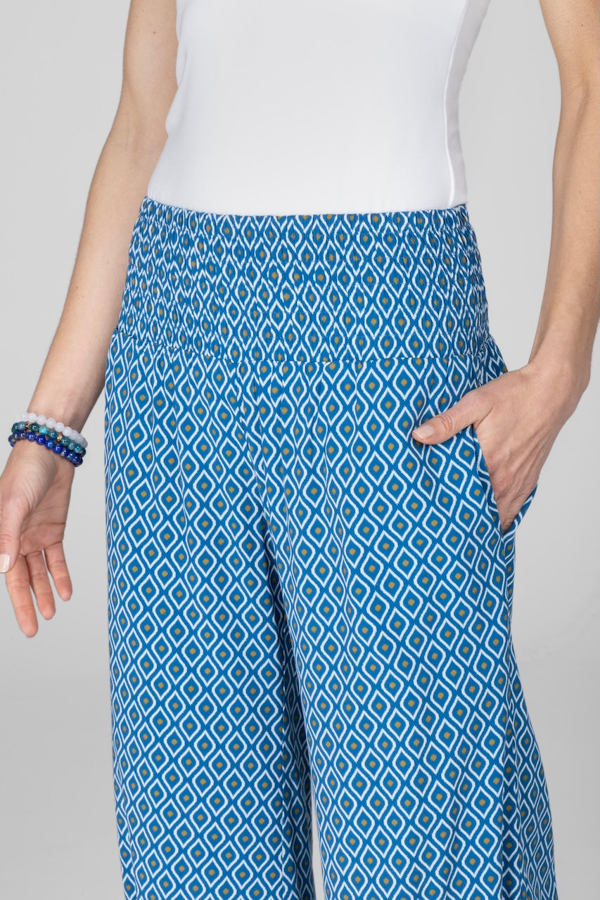 Close up of woman wearing blue pants with geometric print and smocked waistband.