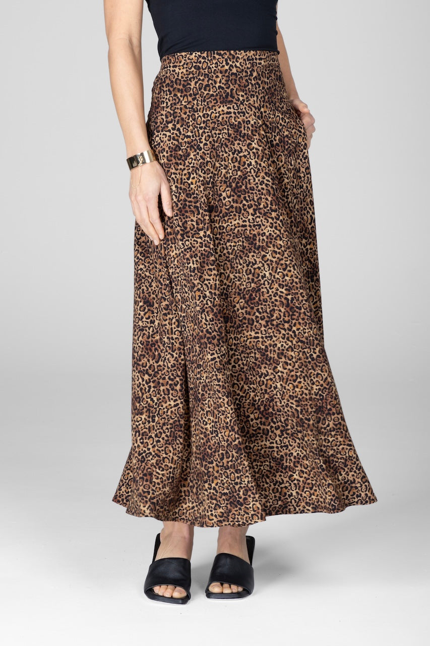 A woman wearing a leopard print maxi skirt with a A-line silhouette, paired with a black top and black strappy sandals.