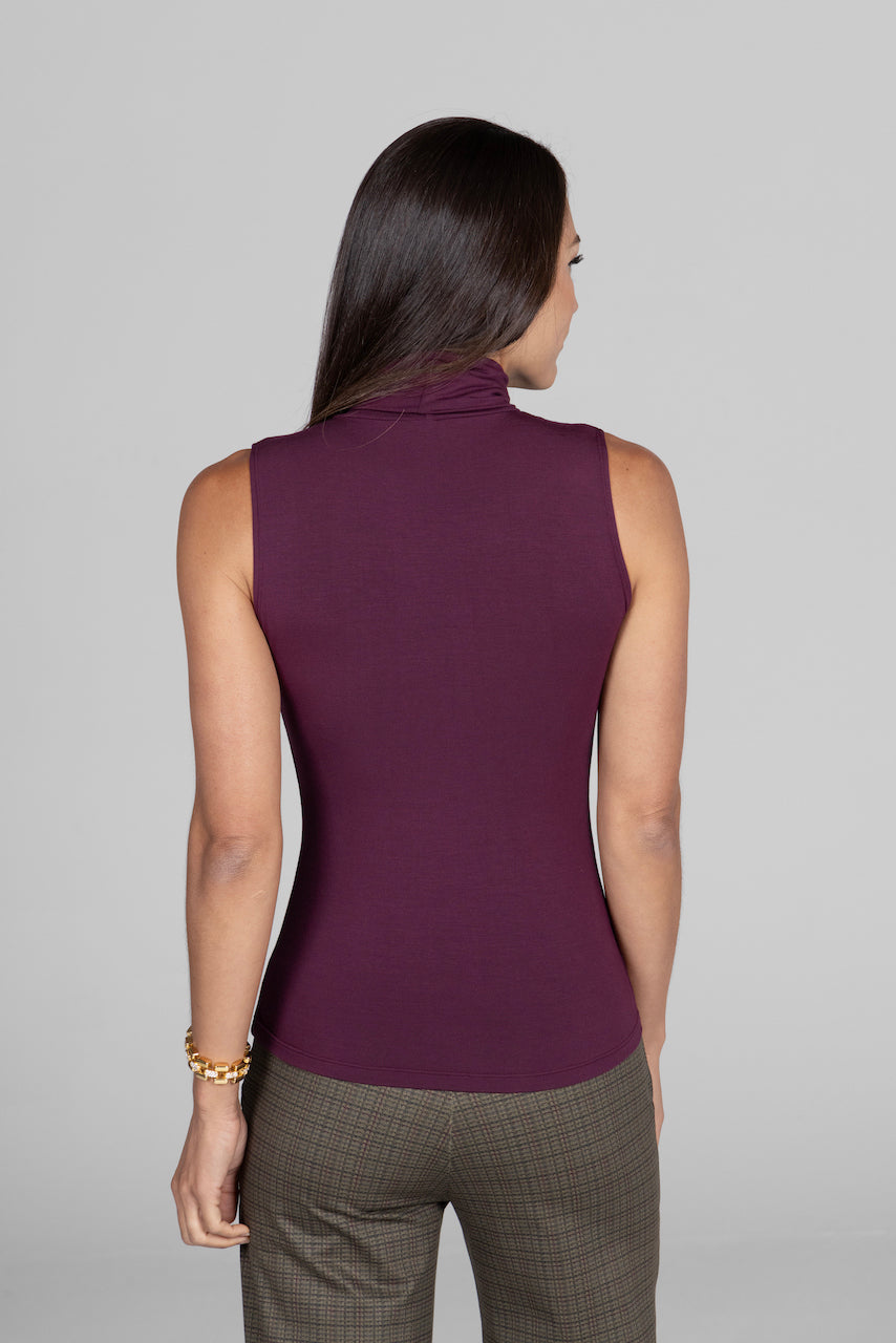 Back view of woman wearing burgundy sleeveless turtleneck untucked