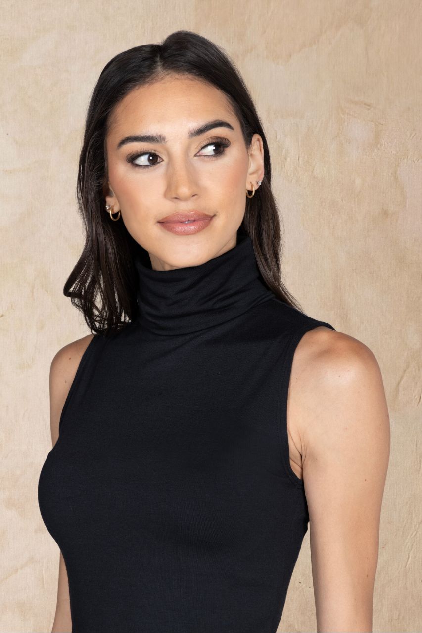 Woman wearing a black sleeveless top against a beige background