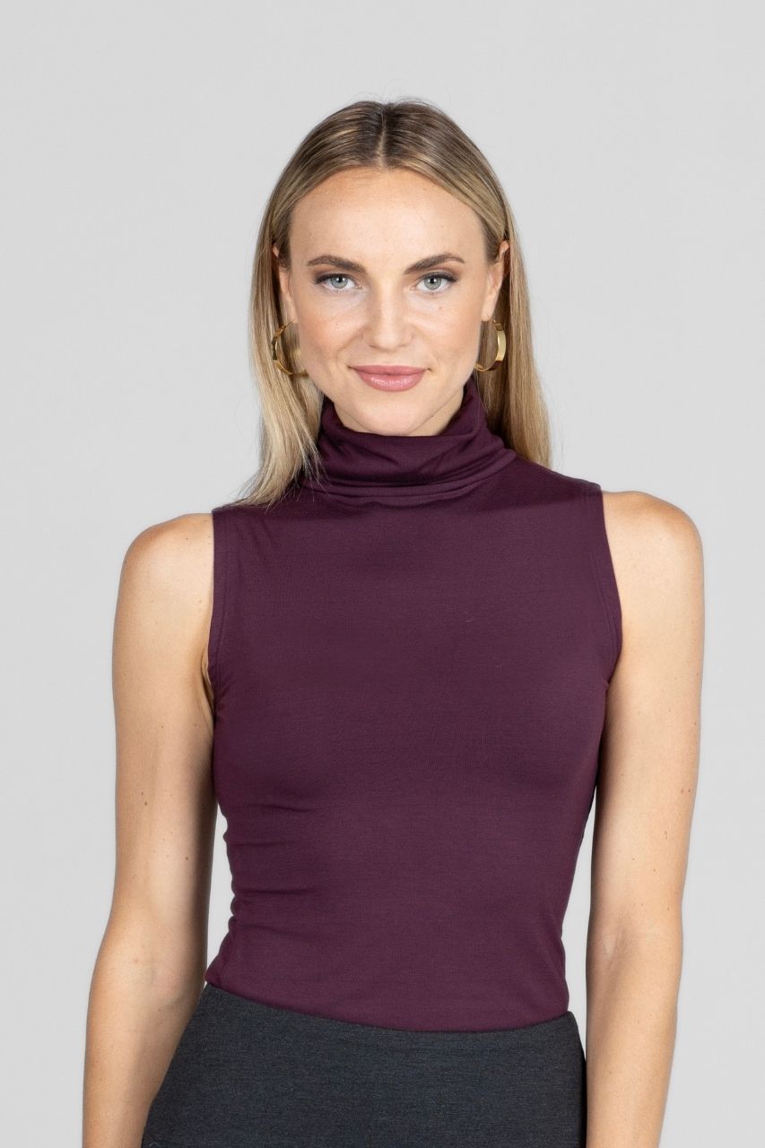 Woman wearing a sleeveless burgundy top against a gray background