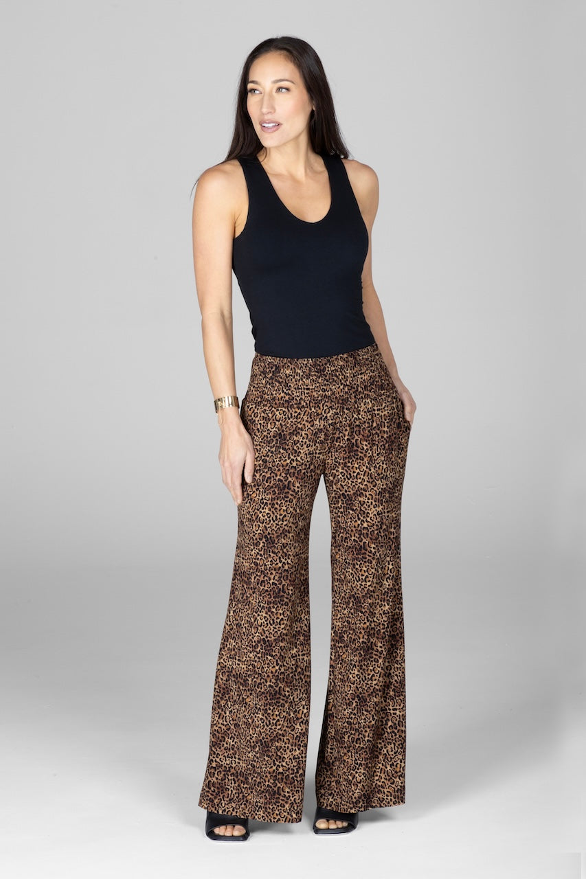 A woman wearing a sleeveless black top and leopard print wide-leg pants.