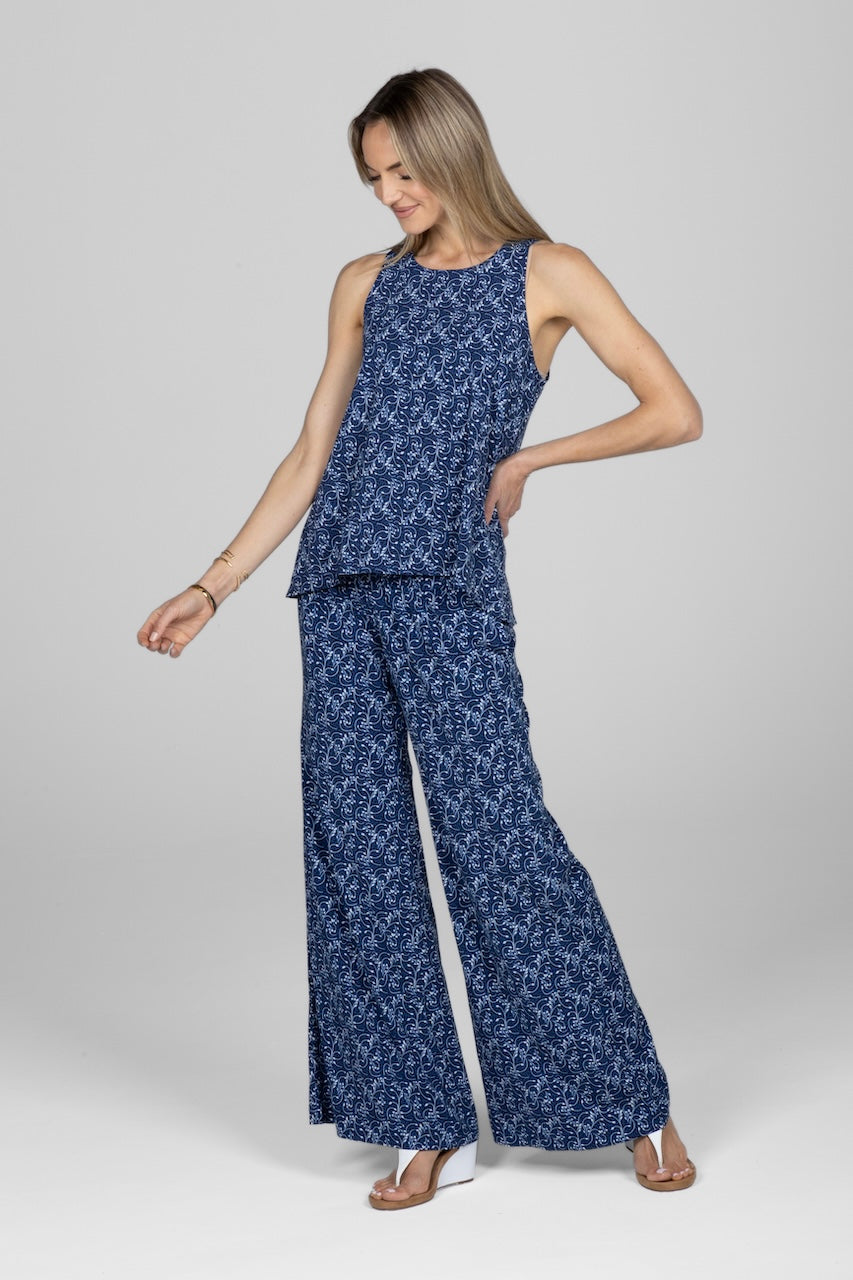 Woman wearing a sleeveless flowy top with blue vine print with matching pants