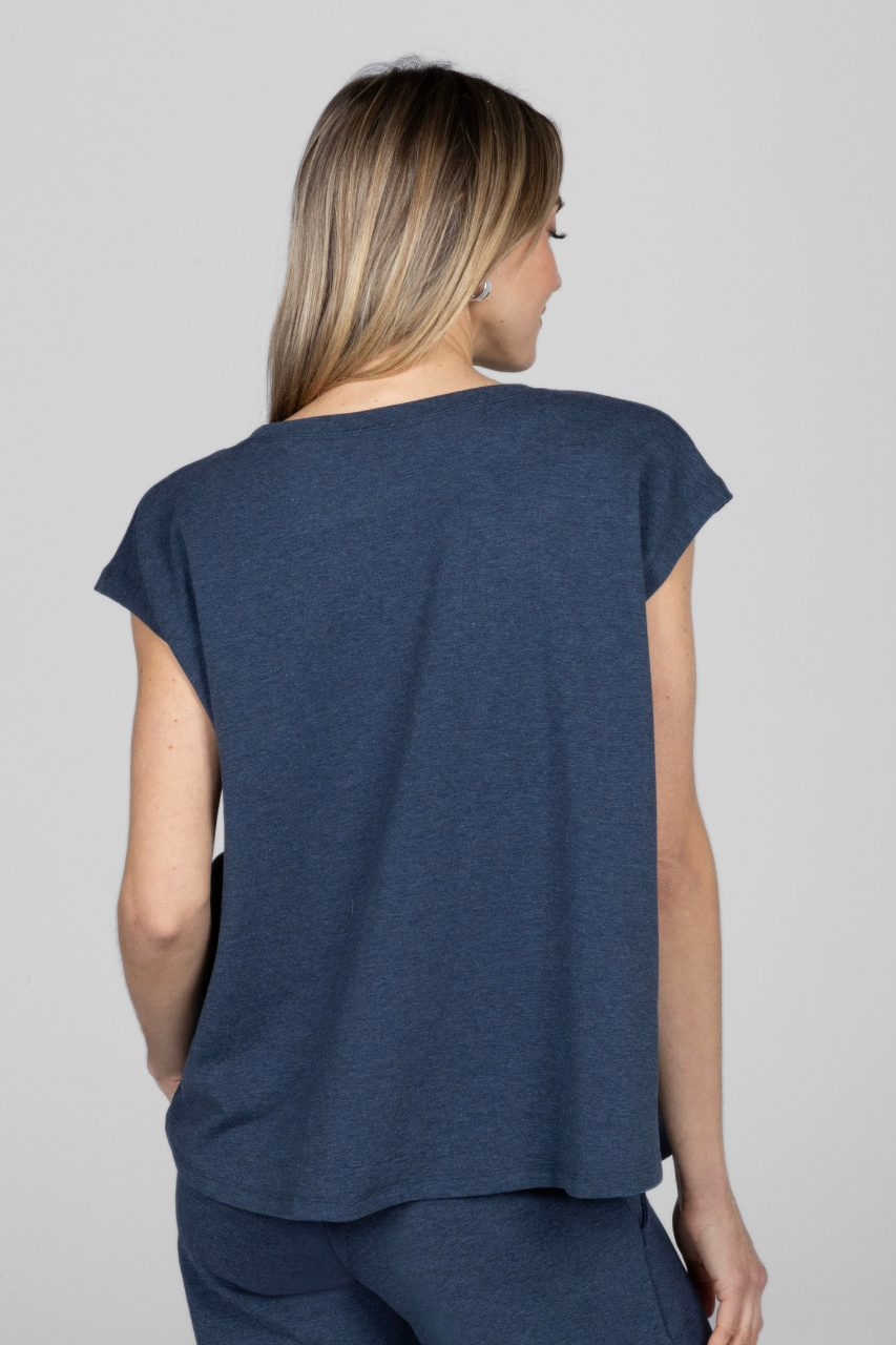 A woman facing away from the camera wearing a blue heather lake boho dolman short sleeve top
