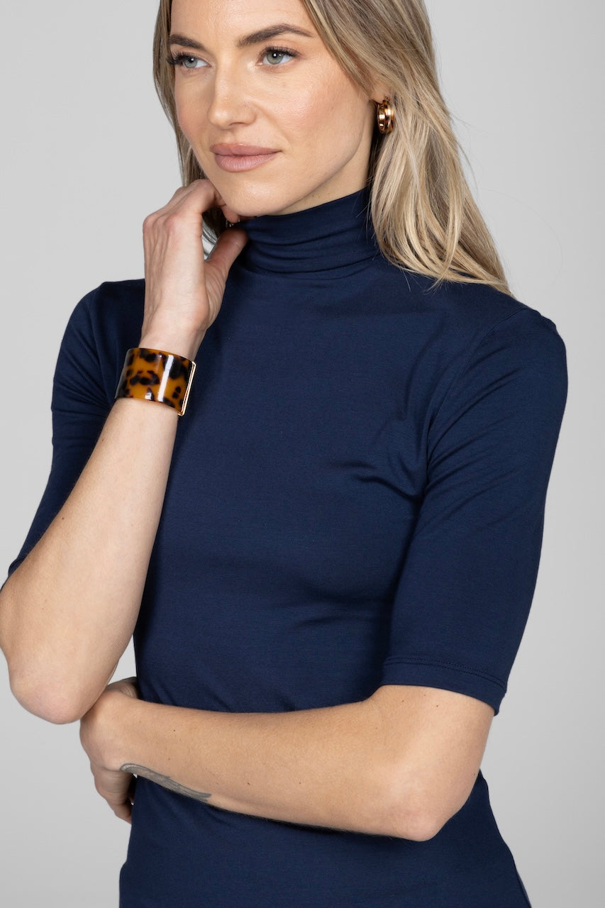 Close up photo of a woman wearing navy blue mock neck short sleeve tee