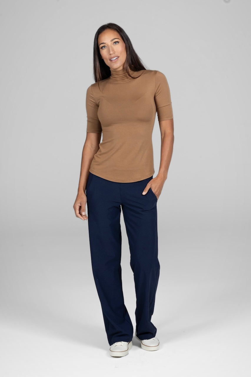 Woman wearing camel brown mockneck tee with navy blue pants and white sneakers