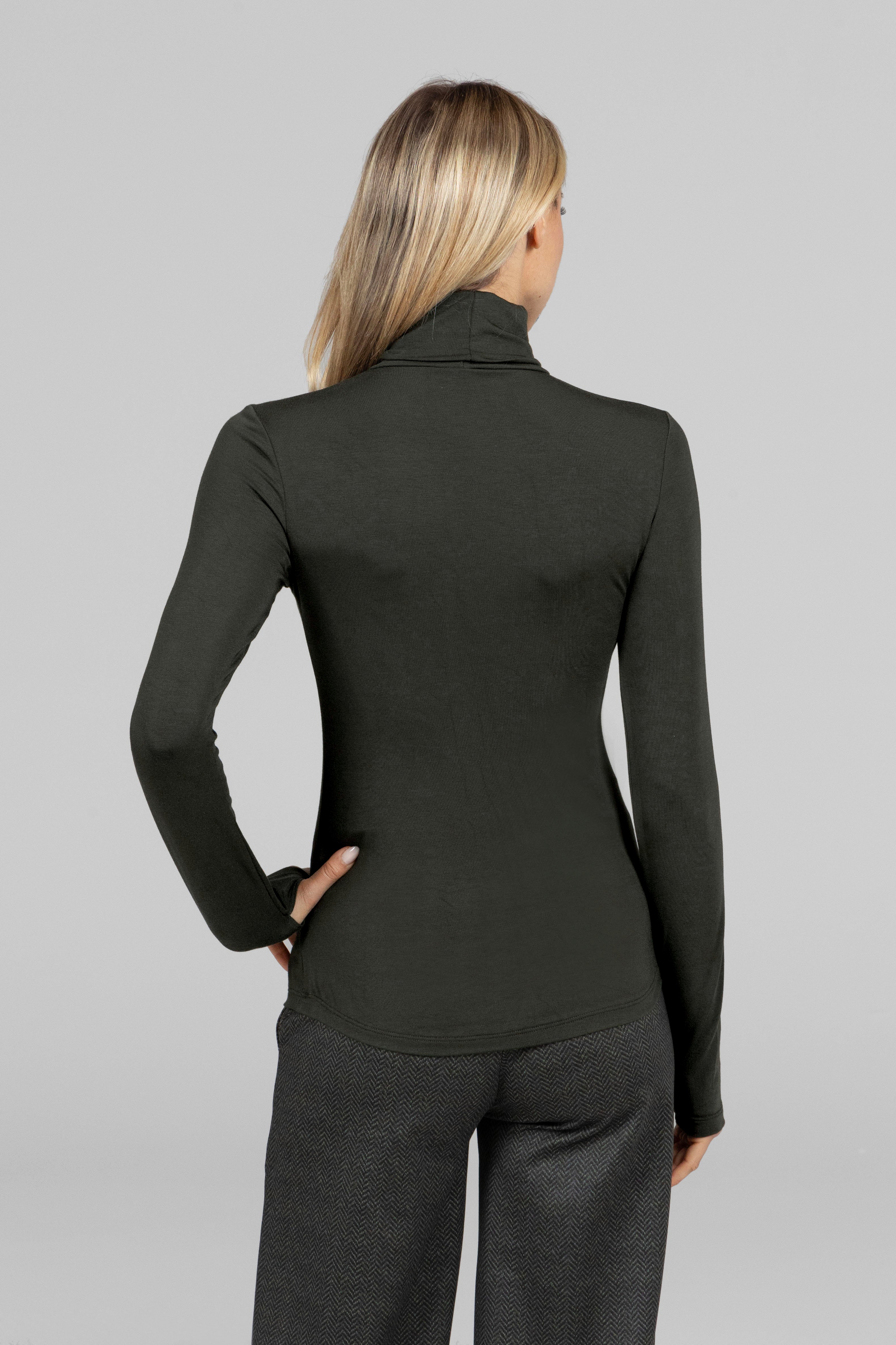 Woman wearing a green long-sleeve top and green tweed pants on a light gray background