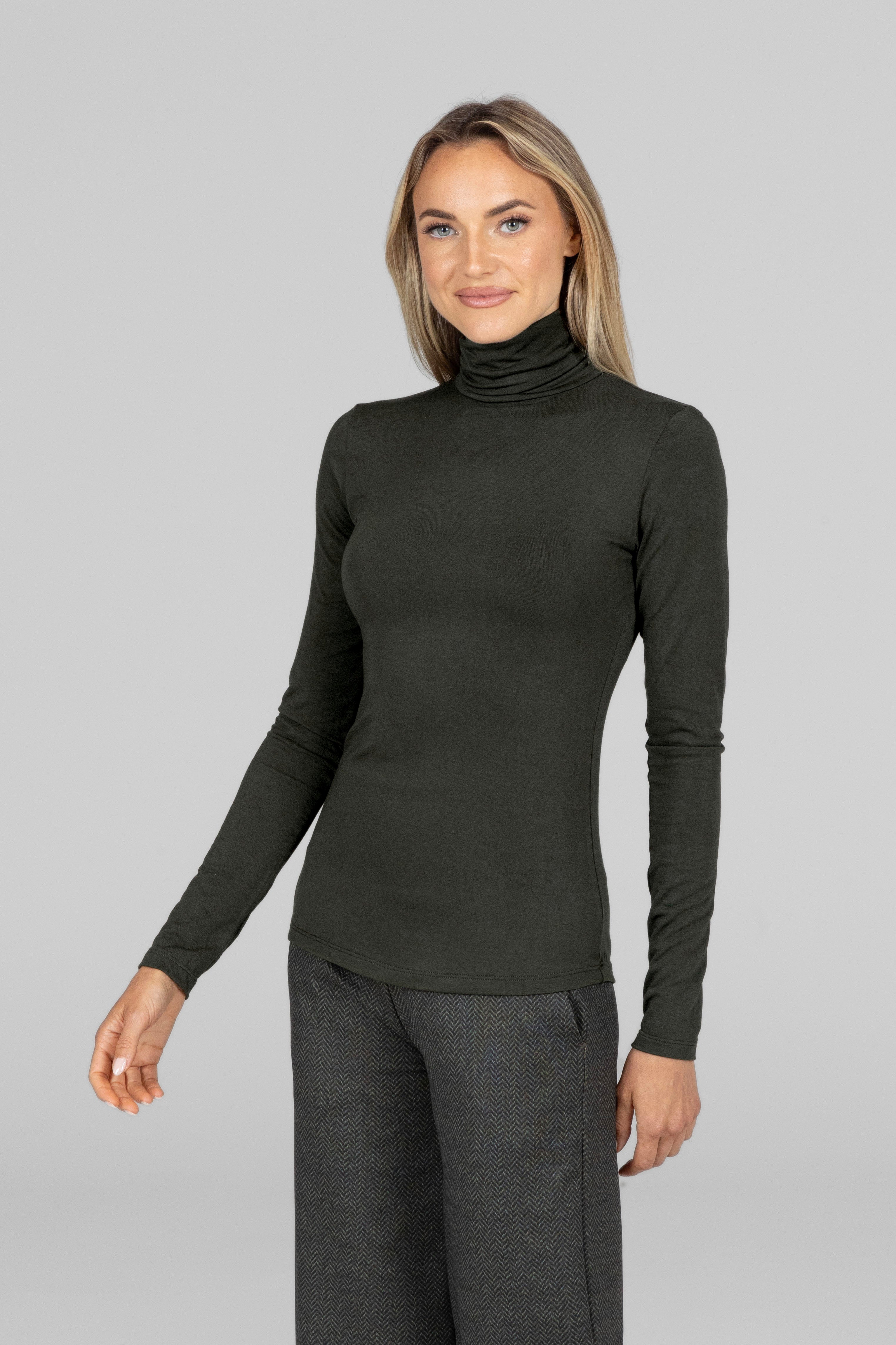 Woman wearing a green turtleneck long sleeve top against a gray background