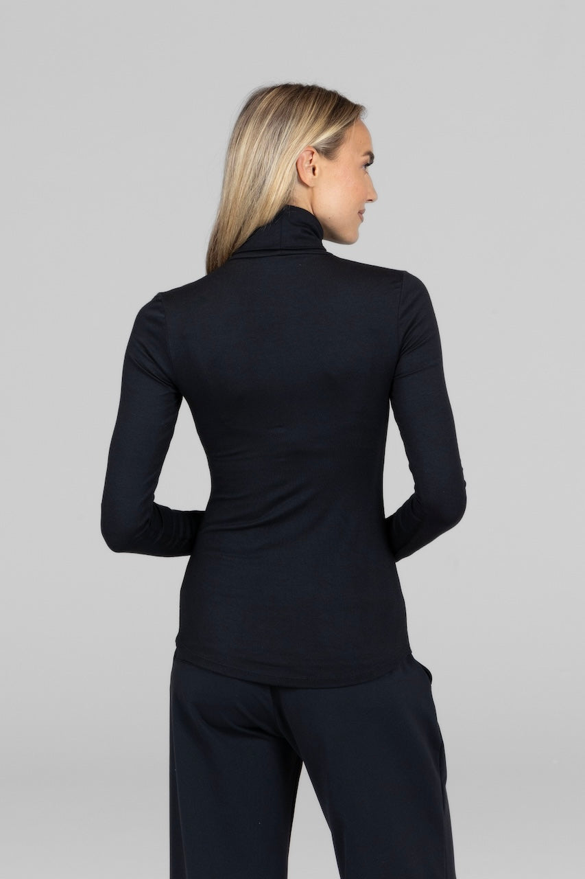 Back view of a woman wearing a black turtleneck and black pants