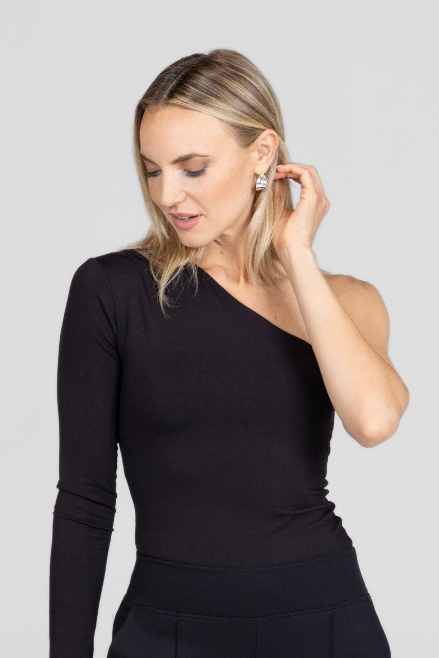 Woman wearing a black one-shoulder long sleeve top against a plain background