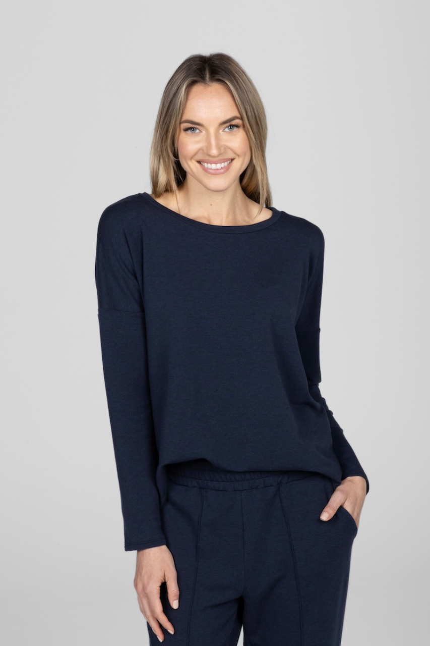 A woman smiling and wearing a navy long sleeve top with a relaxed fit.