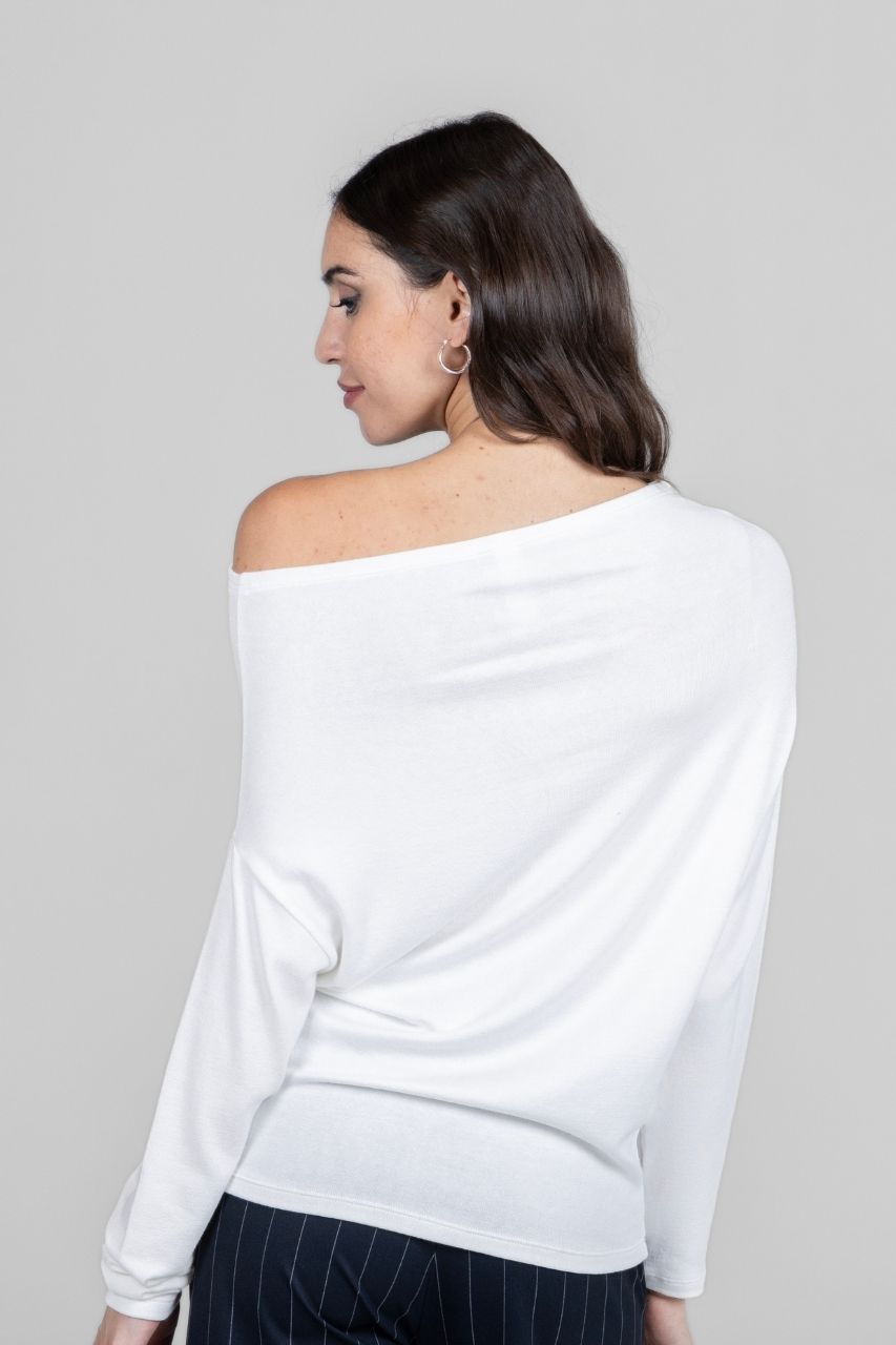 Back view of a woman wearing a white off-shoulder sweater against a gray background