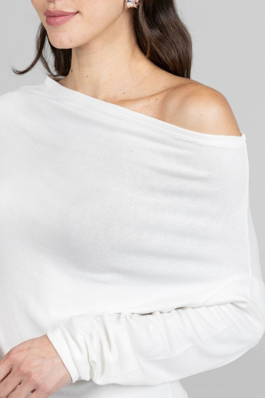 White off-shoulder sweater worn by a woman on a plain background